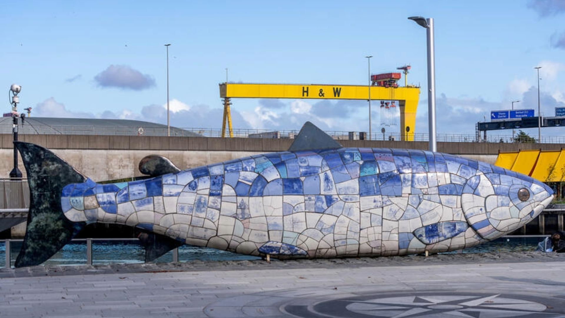 Die Skulptur „Salmon of Knowledge“ am Donegall Quay in Belfast mit dem Kran von Harland und Wolff im Hintergrund.