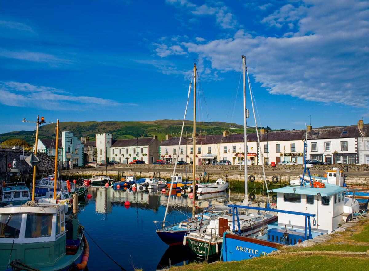 Fischerboote im Hafen von Carnlough, dahinter farbenfrohe Häuser des Dorfes.