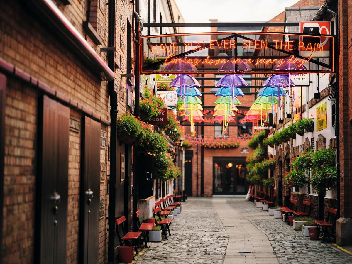Installation aus bunten Blumenkörben und Neon-Regenschirmen vor dem Duke of York Pub in Belfast.
