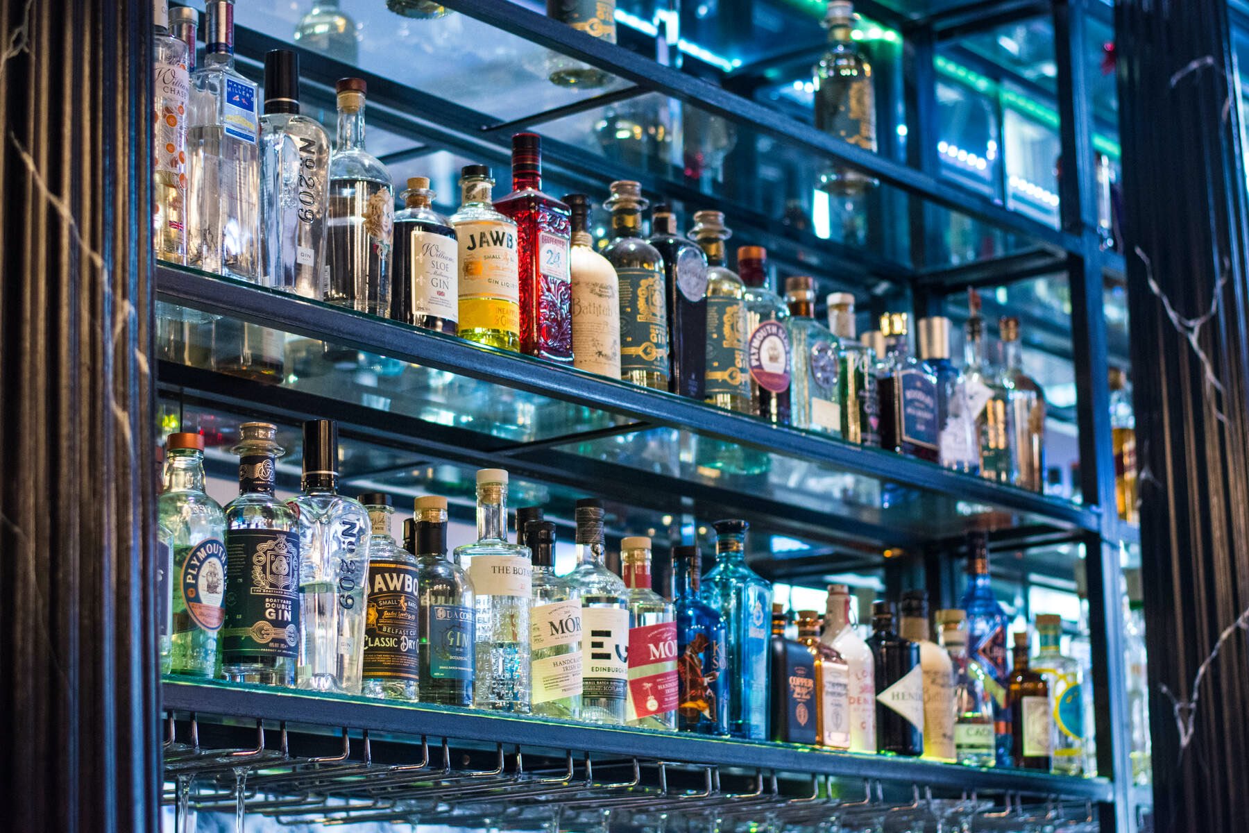 Shelves filled with gin, whiskey, and spirits bottles displayed behind glass in a stylish bar in Enniskillen.