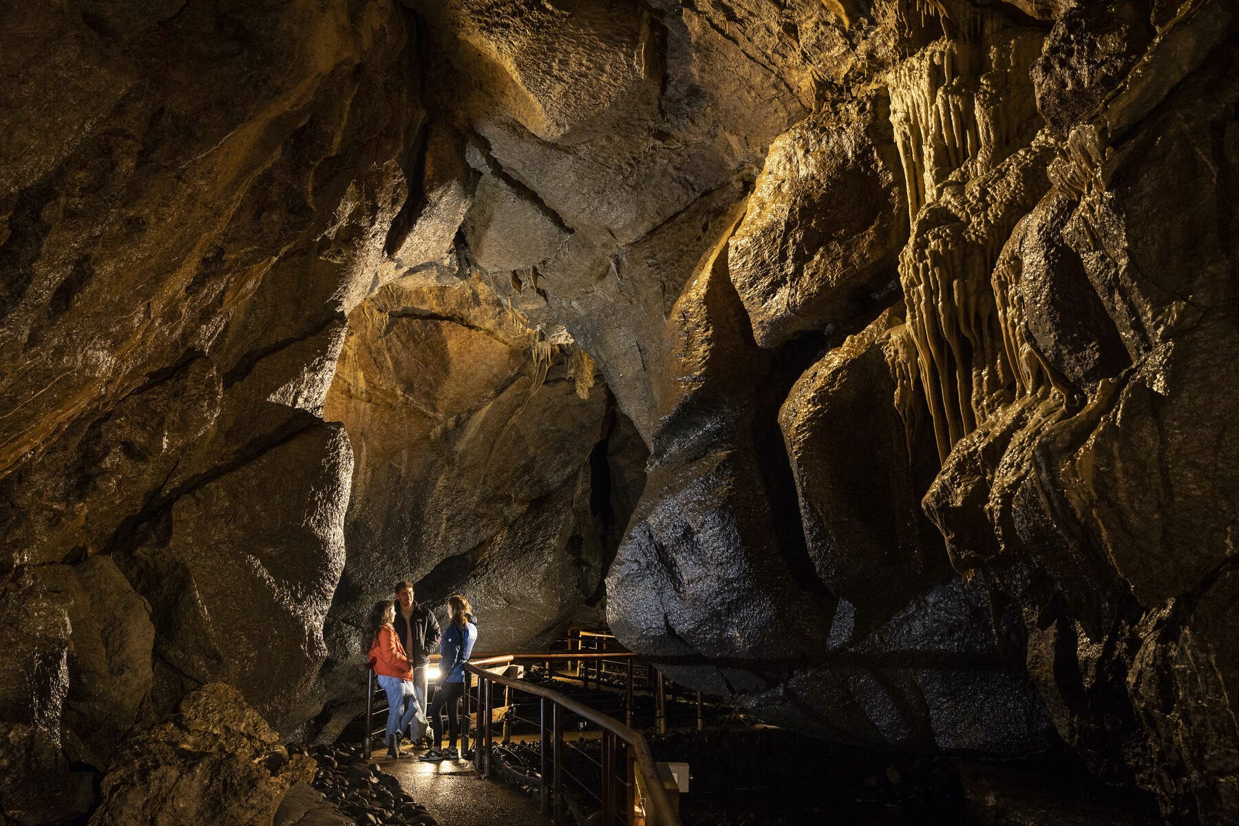 Trois visiteurs se tiennent sur une passerelle dans les profondeurs souterraines des grottes de Marble Arch, dans le comté de Fermanagh.