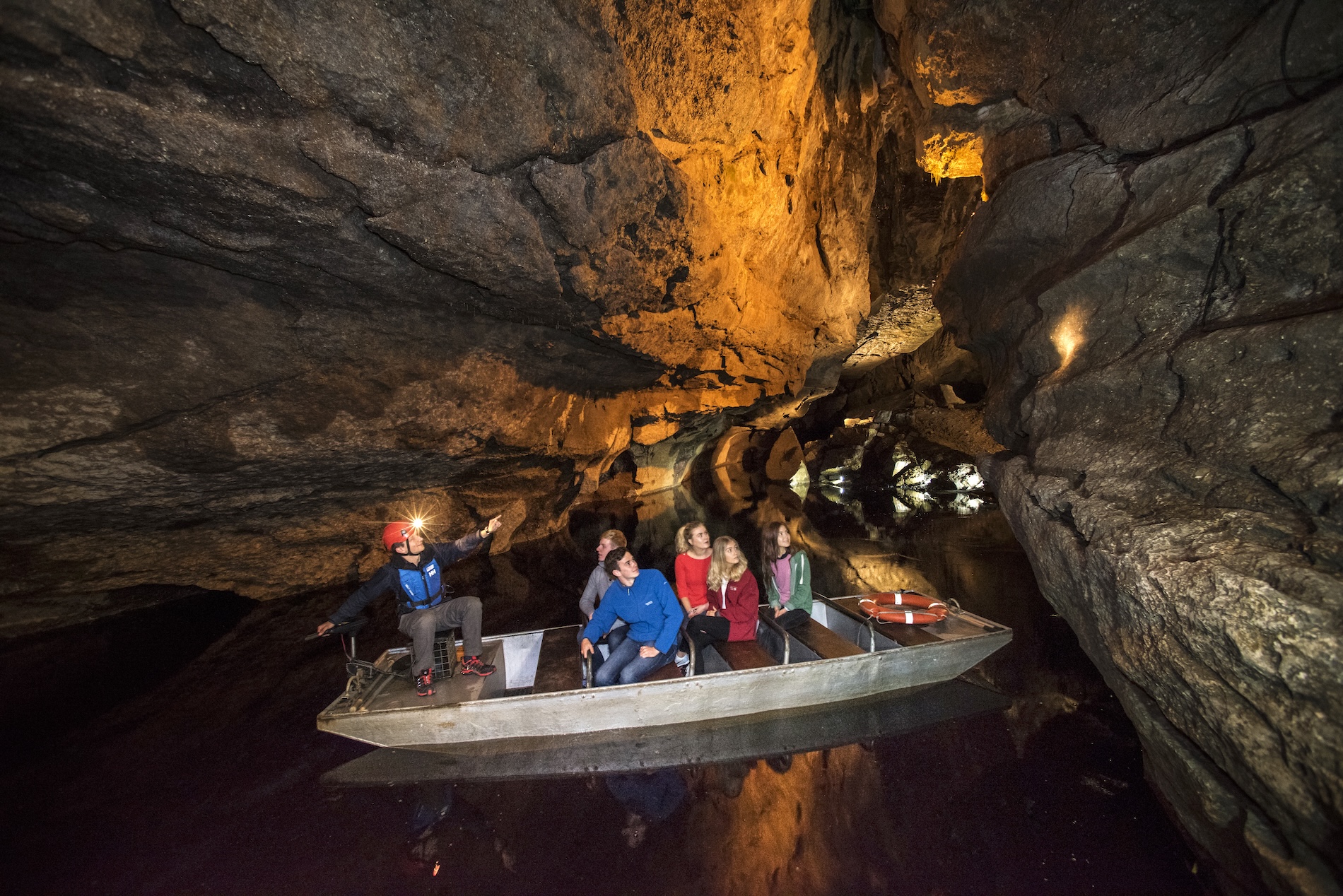 Guide menant une visite en bateau à travers les passages illuminés des grottes de Marble Arch dans le comté de Fermanagh.