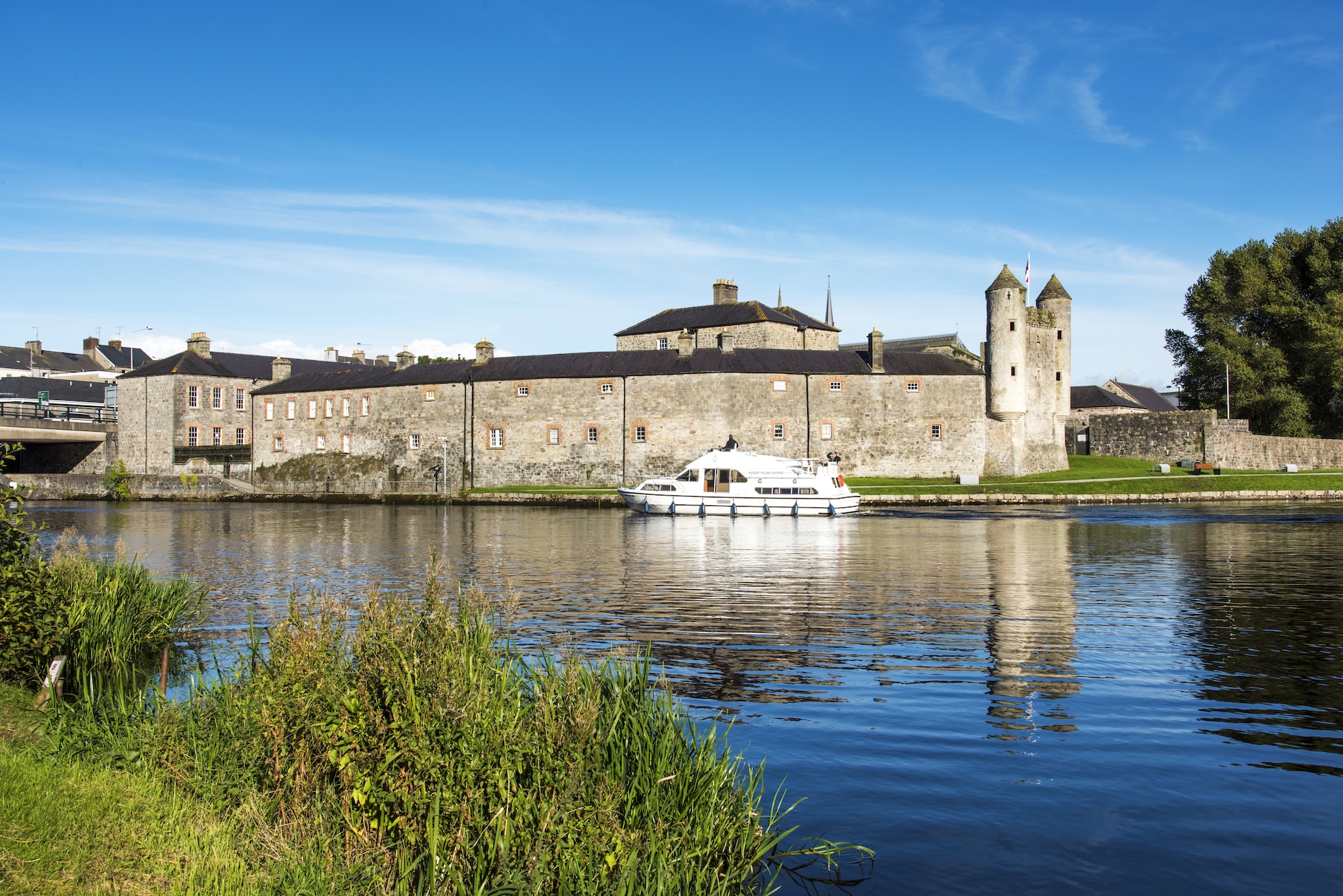 Cruiser sur la rivière Erne à côté des tours et des murs de la cour du château d'Enniskillen.