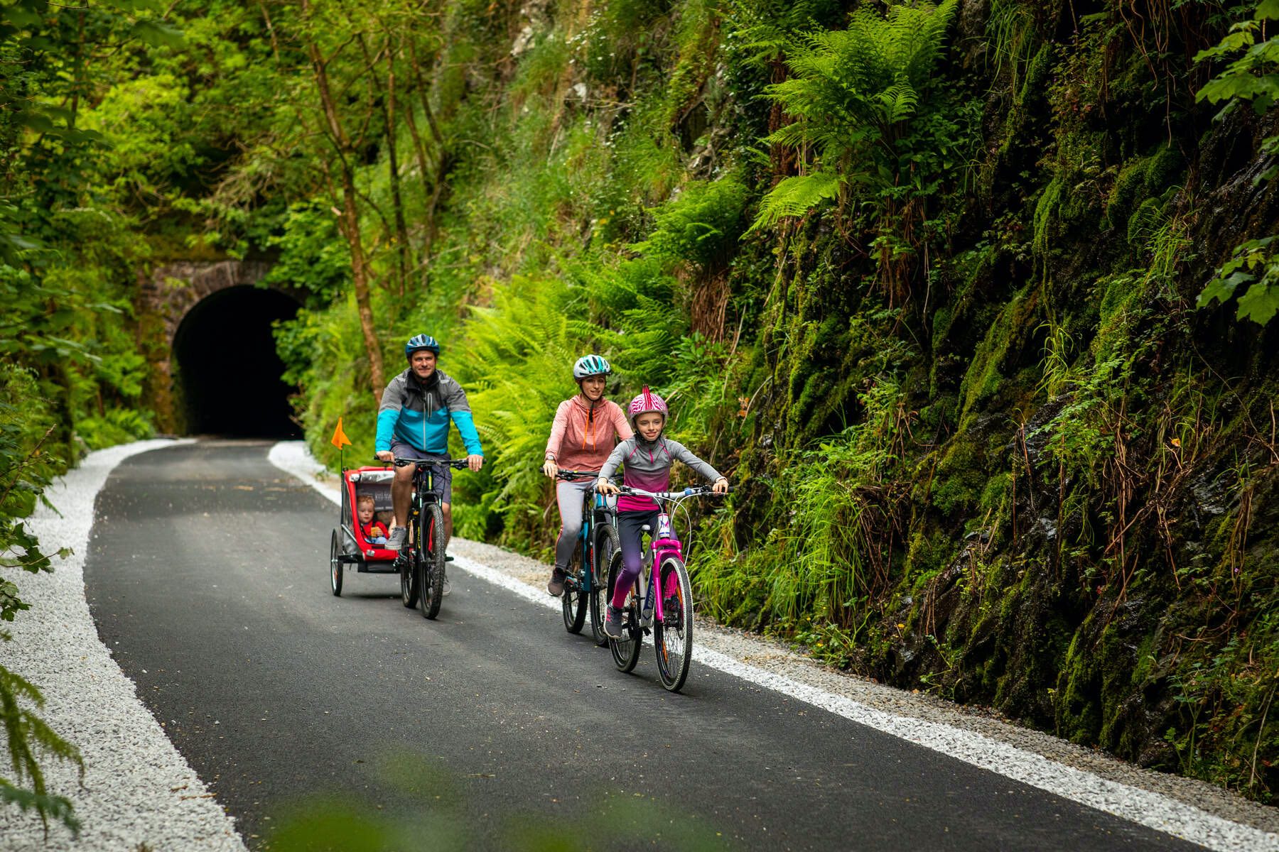 Family cycling past a tunnel on the Limerick Greenway trail.
