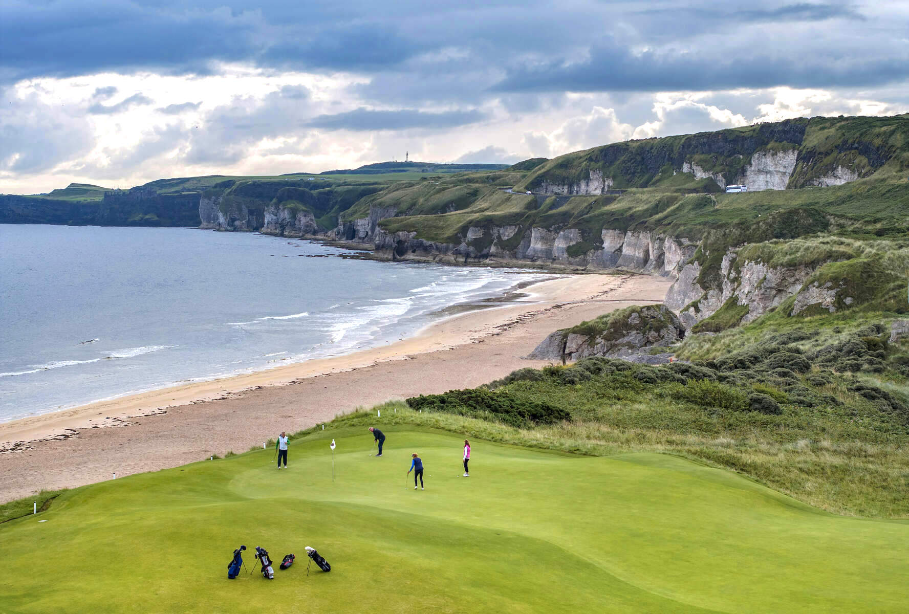 Des golfeurs jouant au club de golf Royal Portrush avec des falaises en arrière-plan.