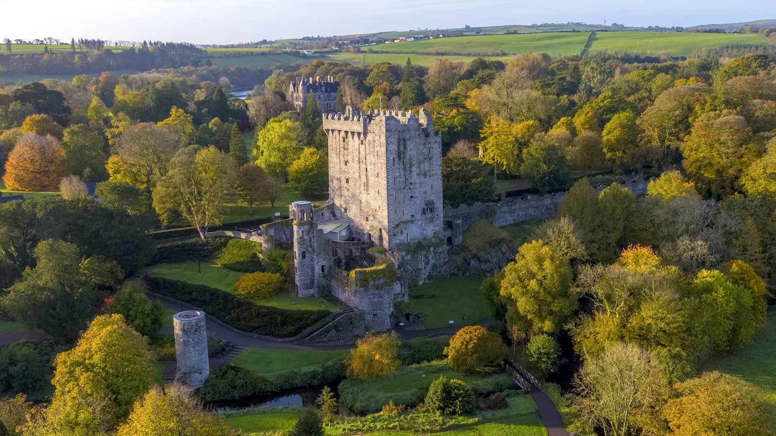 Aerial view of Blarney Castle and gardens surrounded by autumn trees in County Cork.