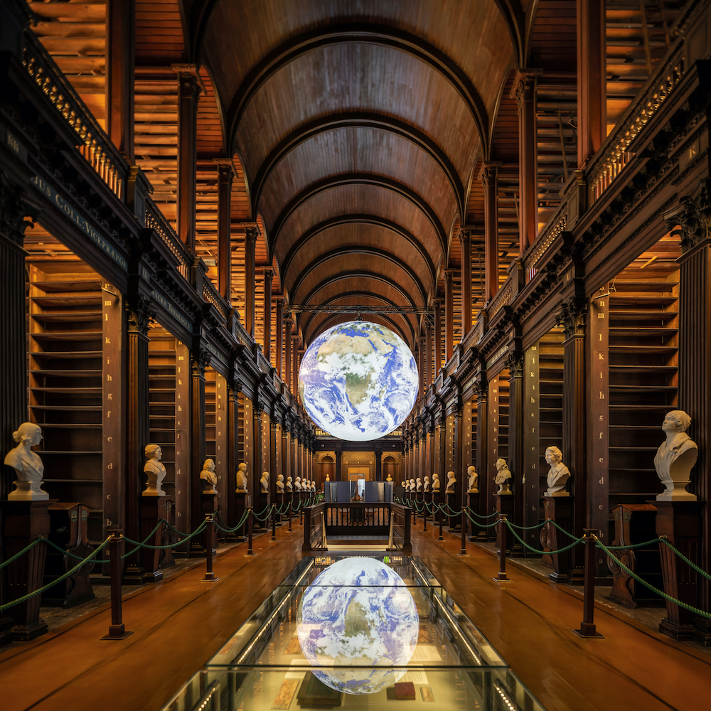 Long Room at Trinity College Dublin Library with Luke Jerram's Gaia Earth installation suspended above the central aisle.