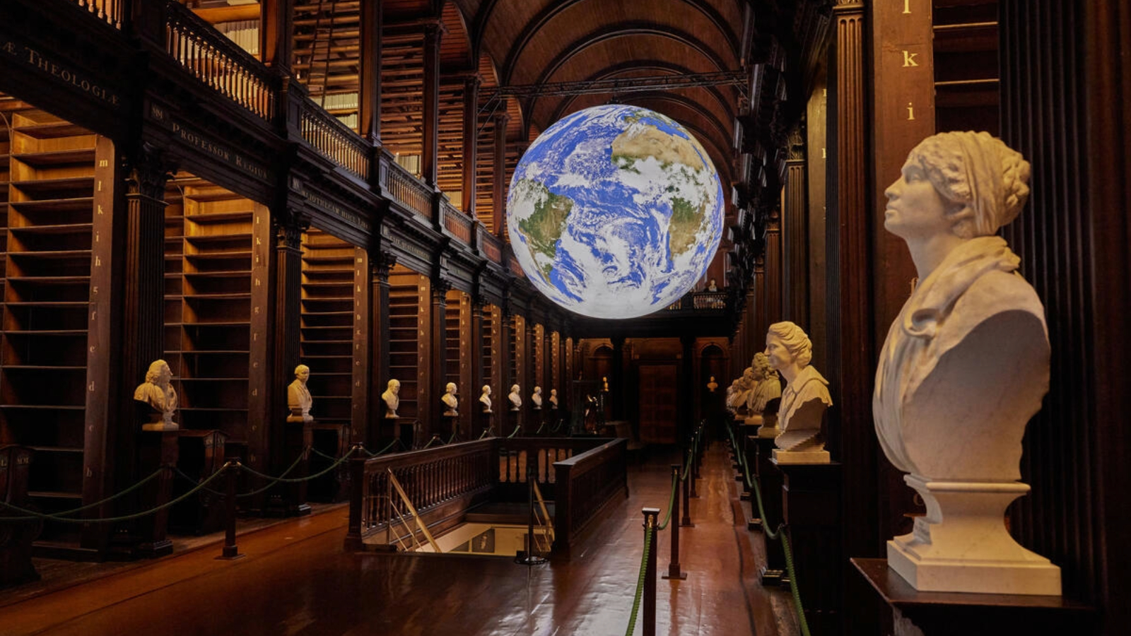 The Long Room library at Trinity College Dublin with marble busts and a suspended Earth globe installation.