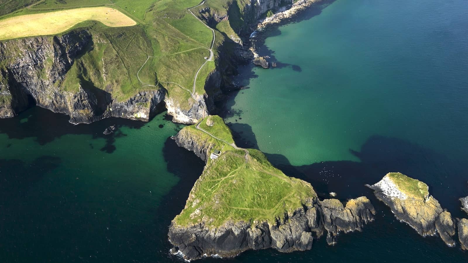 Aerial view of Carrick-a-Rede island and rope bridge surrounded by turquoise waters on the Causeway Coast.