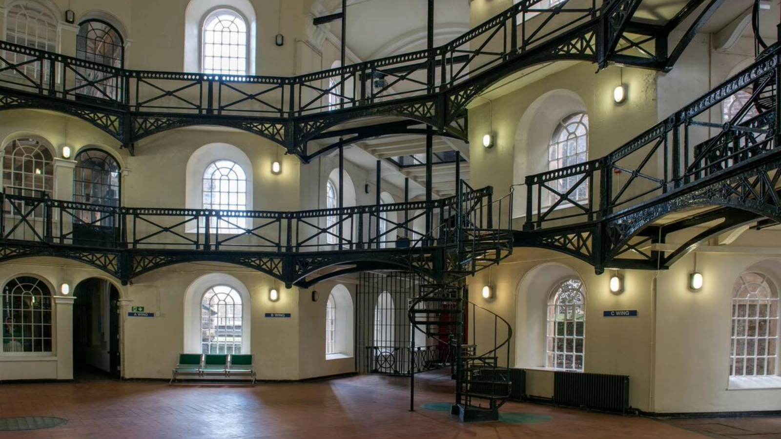 Interior atrium at Crumlin Road Gaol, Belfast, with arched windows, iron galleries and a spiral staircase.