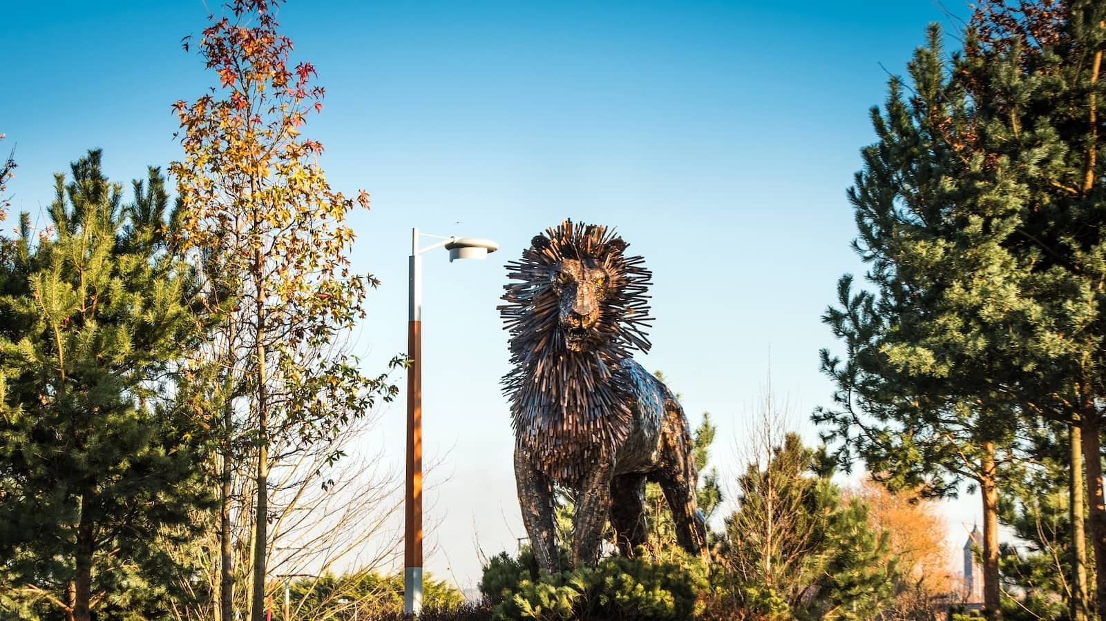Große Metallskulptur eines Löwen namens Aslan zwischen Bäumen auf dem CS Lewis Square in Belfast.