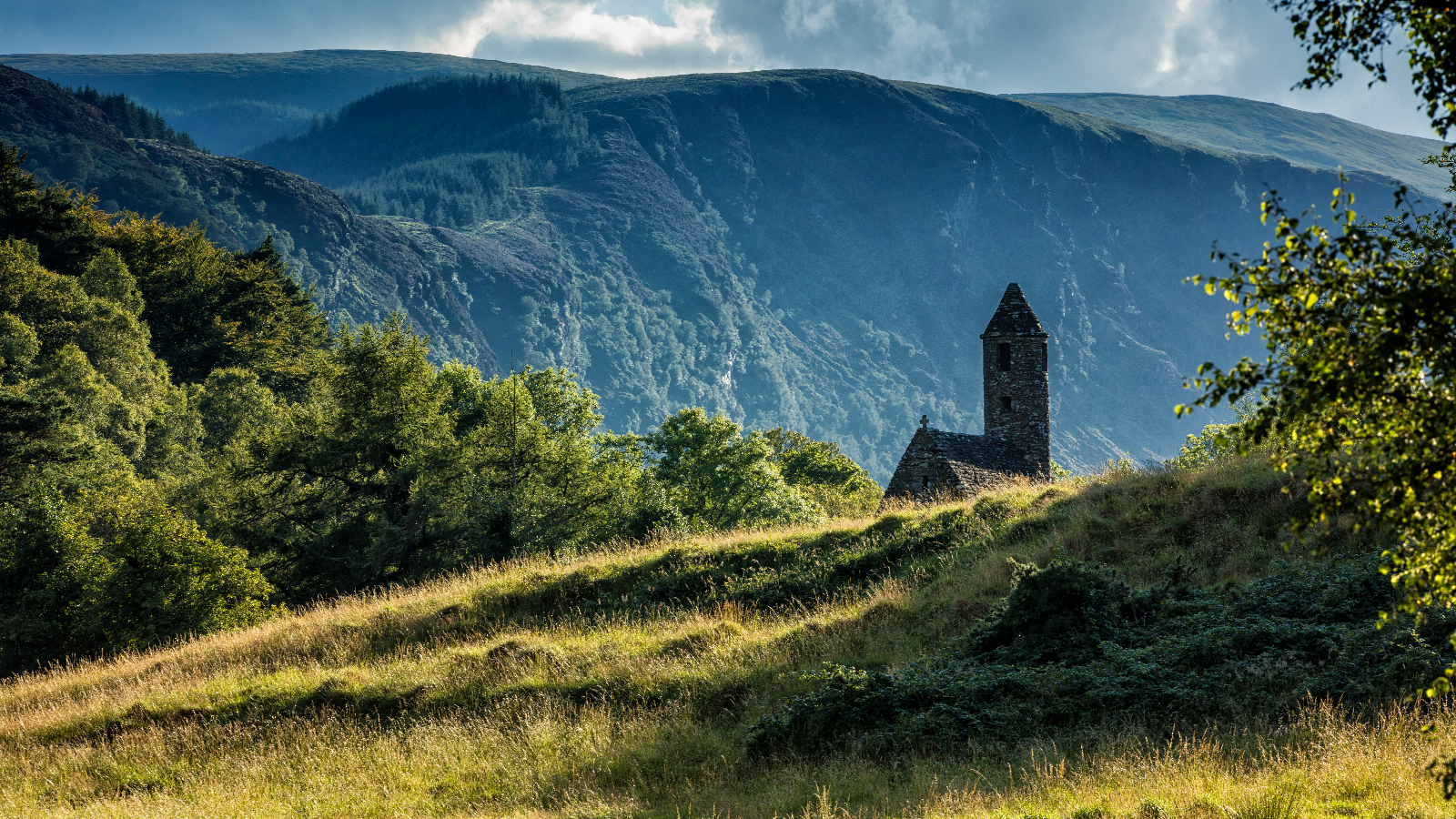 Glendalough round tower and stone church set against the Wicklow Mountains.