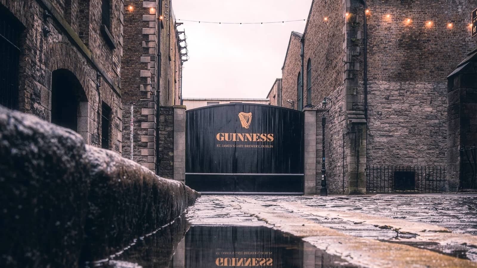 Das Tor des Guinness Storehouse in der St. James's Gate Brewery in Dublin, mit nassen Kopfsteinpflaster nach dem Regen.