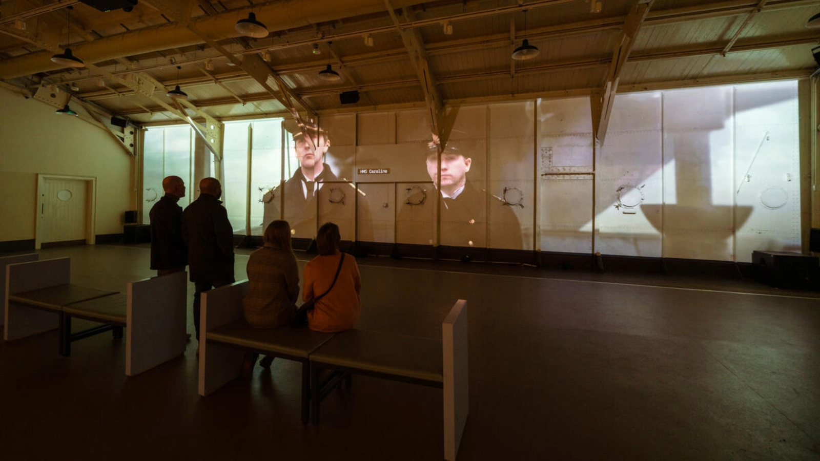 Besucher sehen einen Film, der in der Drill Hall der HMS Caroline in Belfast projiziert wird.