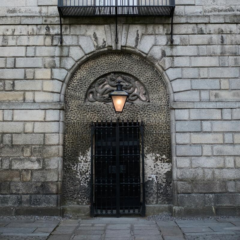 Entrée en pierre ornée avec un portail en fer forgé, des dragons sculptés et une lanterne à la prison de Kilmainham, à Dublin.