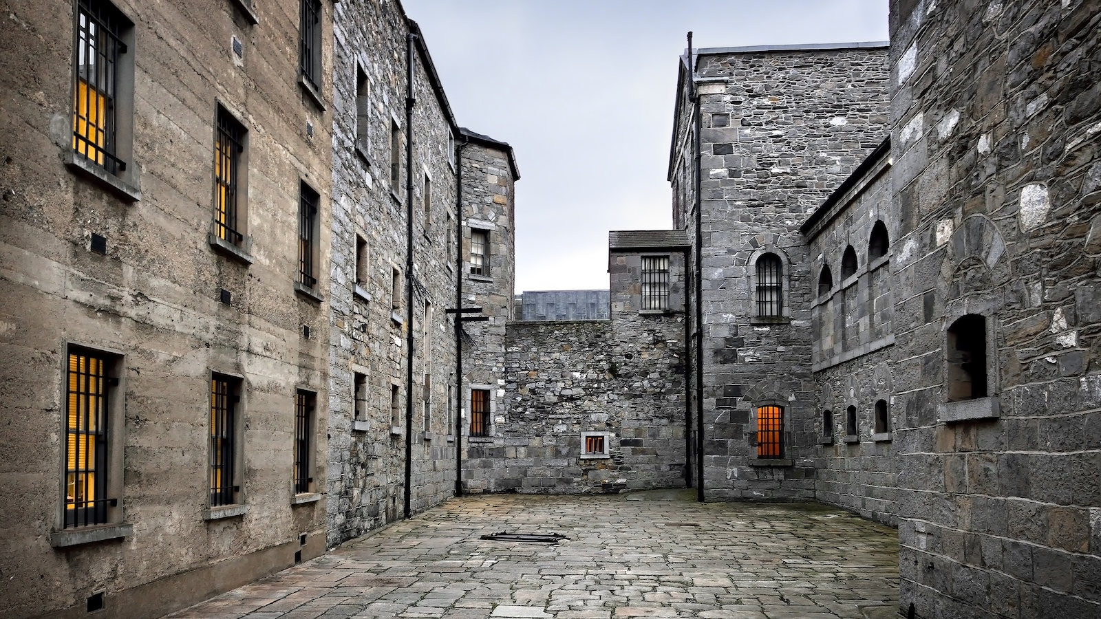Stone courtyard inside Kilmainham Gaol with barred windows and historic prison buildings.
