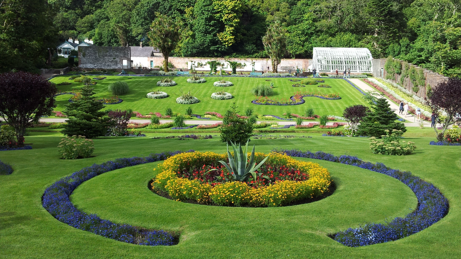 Giardino recintato e formale dell'Abbazia di Kylemore con prati ben curati e montagne sullo sfondo.