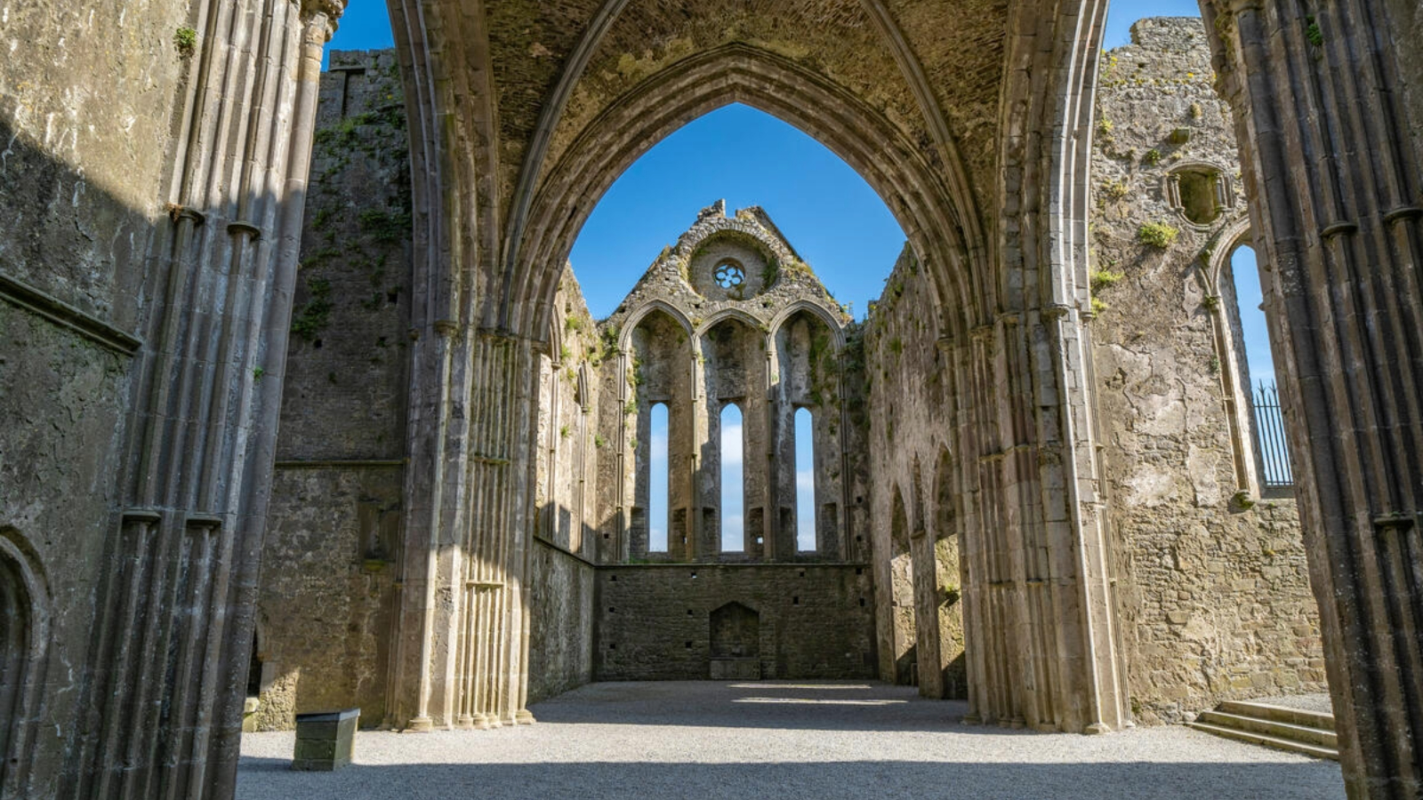 Interior de las ruinas de la catedral denominada Roca de Cashel, mirando a través de un arco de piedra hacia las altas ventanas góticas