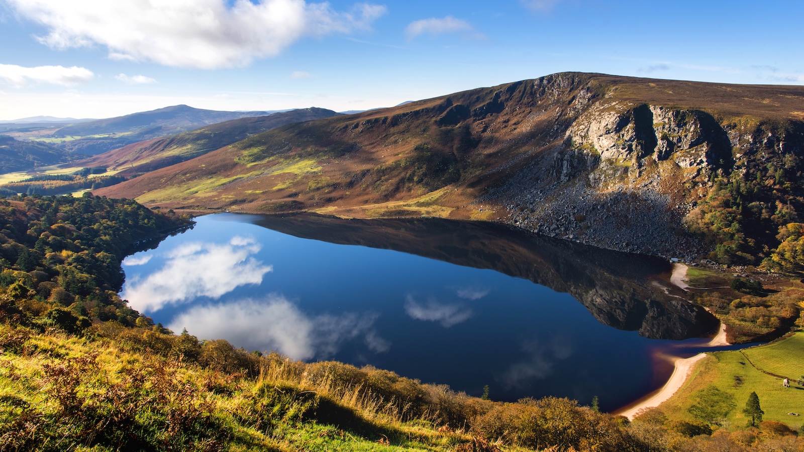 Lough Tay, The Guinness Lake, Co Wicklow. Dark lake with sandy shore beneath cliffs in Wicklow Mountains.