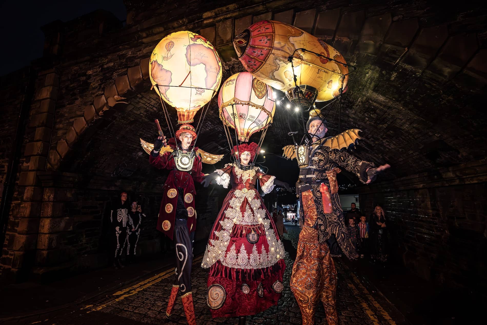 Des artistes en costume, perchés sur des échasses et accompagnés de montgolfières illuminées, défilent dans les rues de Derry~Londonderry à l'occasion d'Halloween.