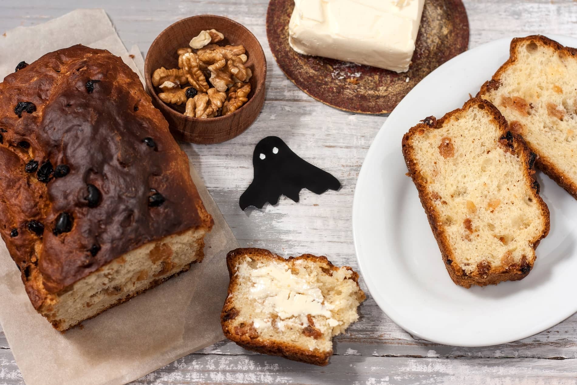 Traditional Irish barmbrack served with butter, sliced and ready to enjoy, alongside walnuts and dried fruit.