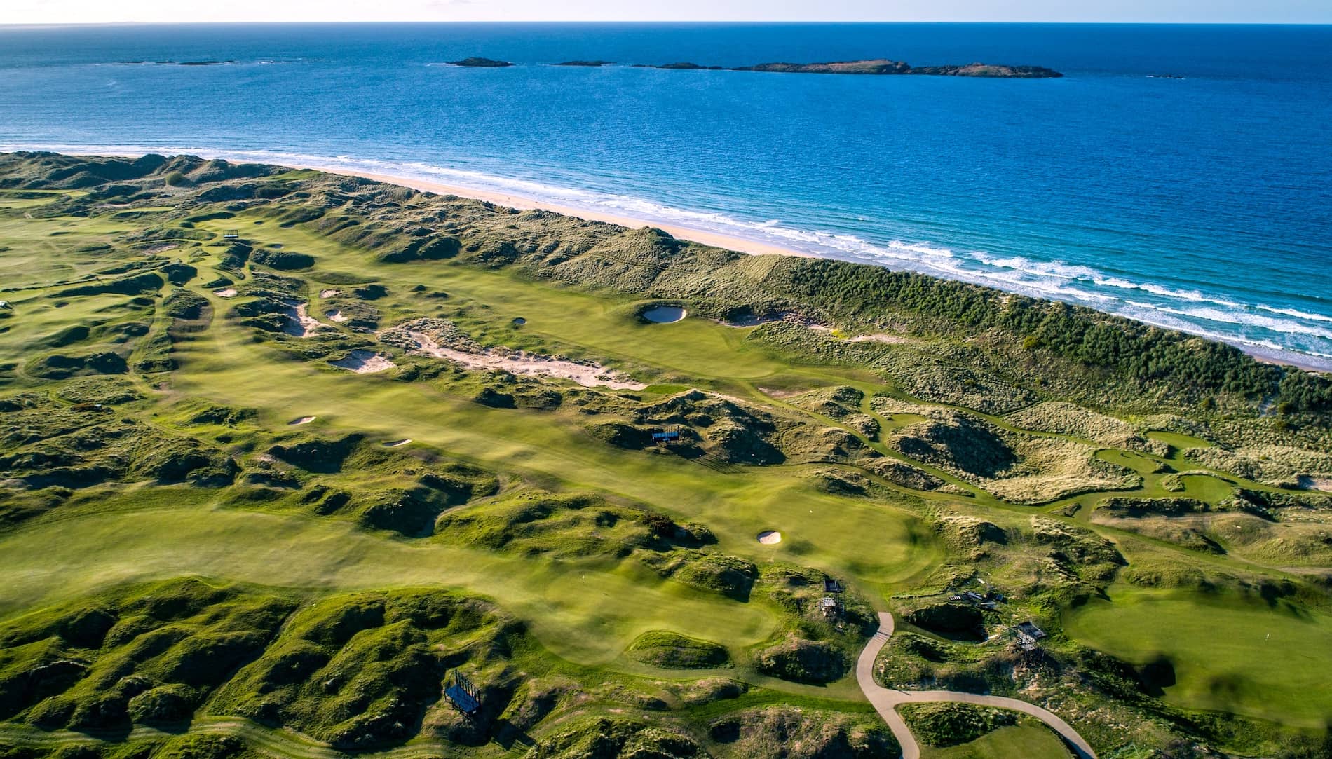 Aerial view of Royal Portrush Golf Club with rolling links fairways overlooking the Atlantic Ocean.