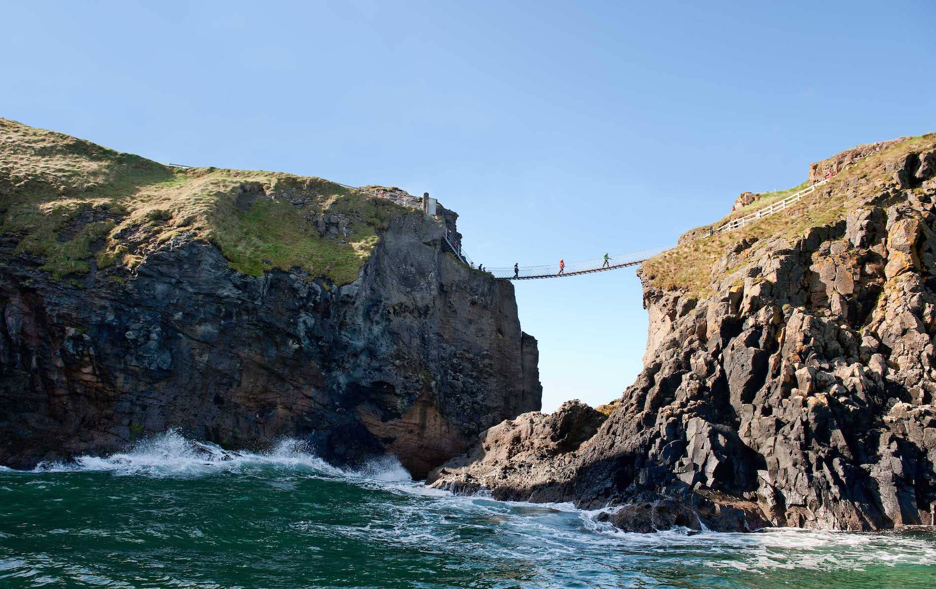 Besucher überqueren die Carrick-a-Rede-Seilbrücke in der Grafschaft Antrim, die zwischen dramatischen Klippen über dem Atlantik gespannt ist.