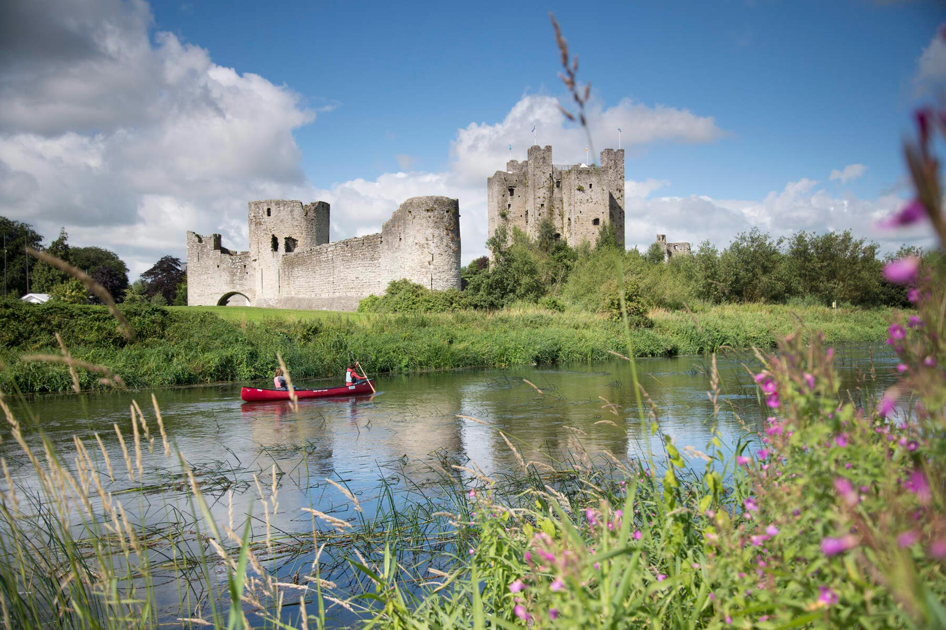 Mittelalterliche Ruinen einer Steinburg mit hohen Türmen und Mauern, die sich in einem ruhigen Fluss in der Grafschaft Meath, Irland, spiegeln.