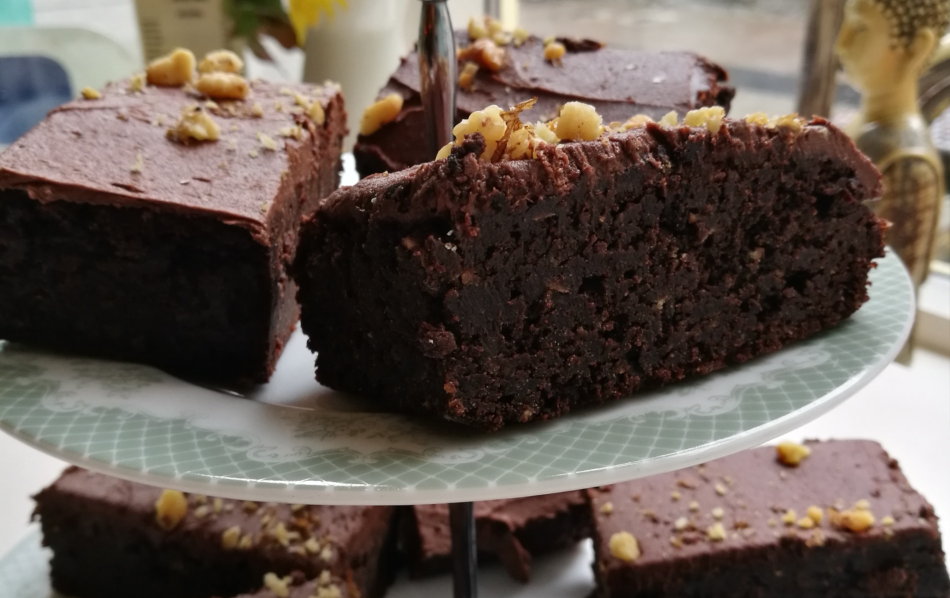 Rich chocolate brownies topped with walnuts on a cake stand.