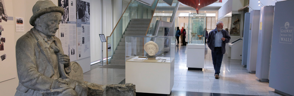Interior of Galway City Museum with exhibits, statues and visitors exploring heritage displays.