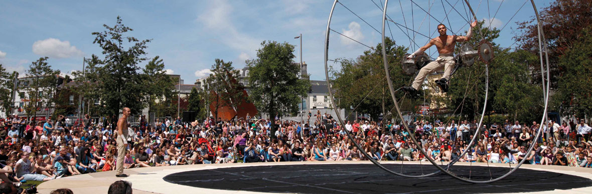 Outdoor performance with acrobat and large crowd at Galway International Arts Festival.