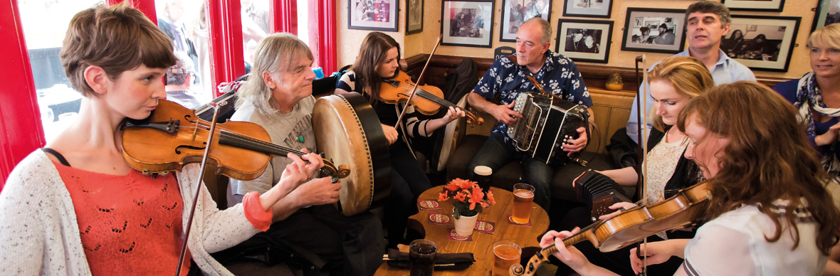 Musicians playing fiddle, bodhrán and accordion in a lively Galway pub session.