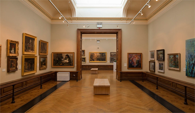 Luminosa sala della galleria con pavimenti in legno, lucernario e quadri incorniciati alla Crawford Art Gallery, Cork.
