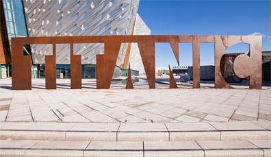 Musée Titanic Belfast avec une sculpture de l'inscription « Titanic » de couleur rouille devant le bâtiment.