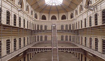 Das historische Innere der Kilmainham-Haftanstalt in Dublin, mit gestaffelten Gehwegen und einer zentralen Metalltreppe.
