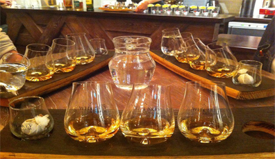Bicchieri di whiskey irlandese serviti su tavole di legno durante una degustazione al Museo del Whiskey Irlandese di Dublino.