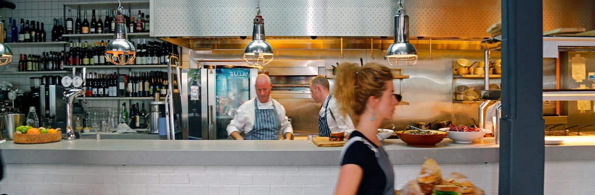 Chefs prepare food in a modern Irish kitchen with wine bottles on display at the Woollen Mills, Dublin.