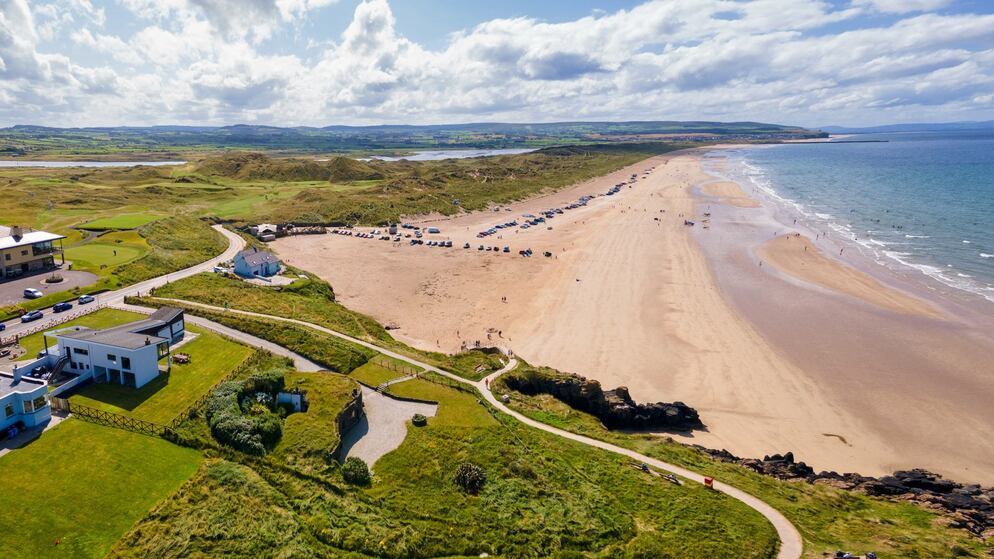 Wide sandy beach backed by grassy dunes and a golf course at Strand Head, County Londonderry.