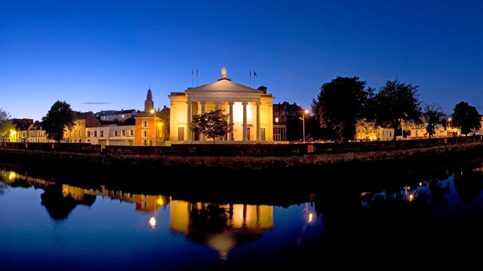 Das Rathaus und die georgianischen Gebäude in Cork spiegeln sich in der Abenddämmerung unter einem tiefblauen Abendhimmel im Fluss Lee.