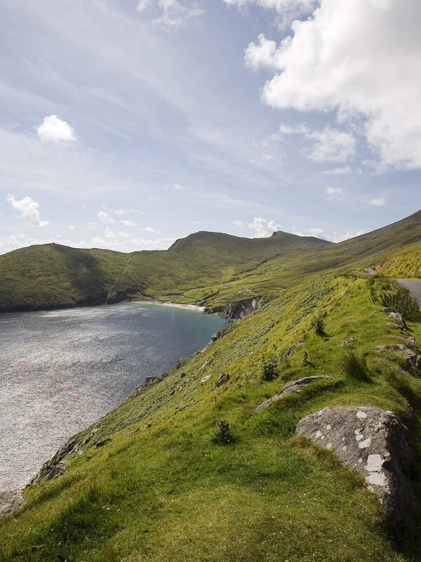 Mountain backdrop with winding road alongside a lake on a cloudy day in Connemara, Ireland.