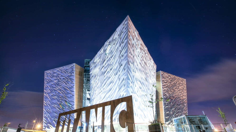La cúpula y los pilares del Ayuntamiento de la ciudad de Belfast vistos a través de las ramas de los árboles en un despejado día de cielo azul.