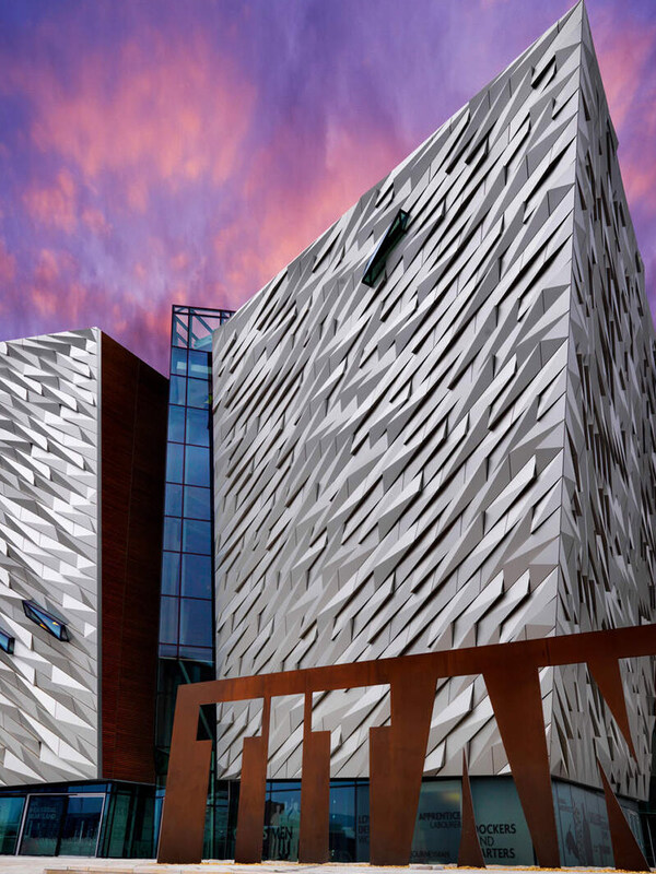 Il suggestivo museo Titanic Belfast dal design angolare illuminato dal cielo rosa del tramonto nell'Irlanda del Nord.