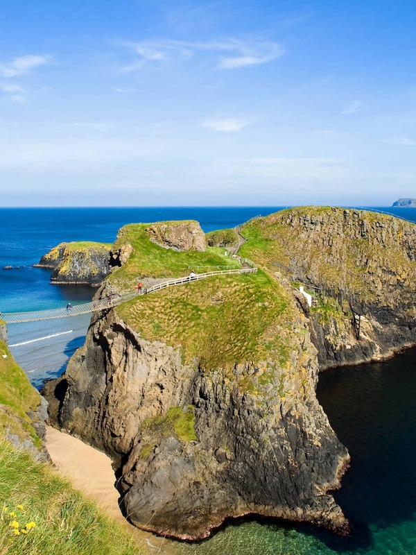 Visitors cross the Carrick-a-Rede Rope Bridge, suspended between two rugged sea cliffs on the Antrim coast.