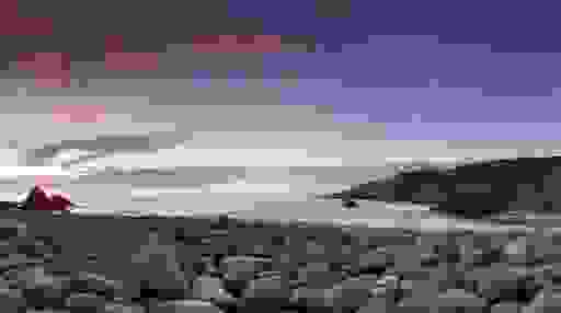 Sunset over pebble beach with waves breaking against cliffs at Bloody Foreland, County Donegal.