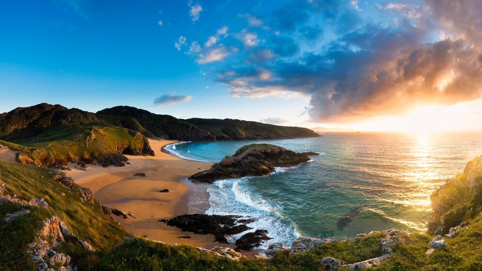 Golden-hour view of Murder Hole Beach in County Donegal, with cliffs, turquoise surf and sunlit Atlantic horizon.