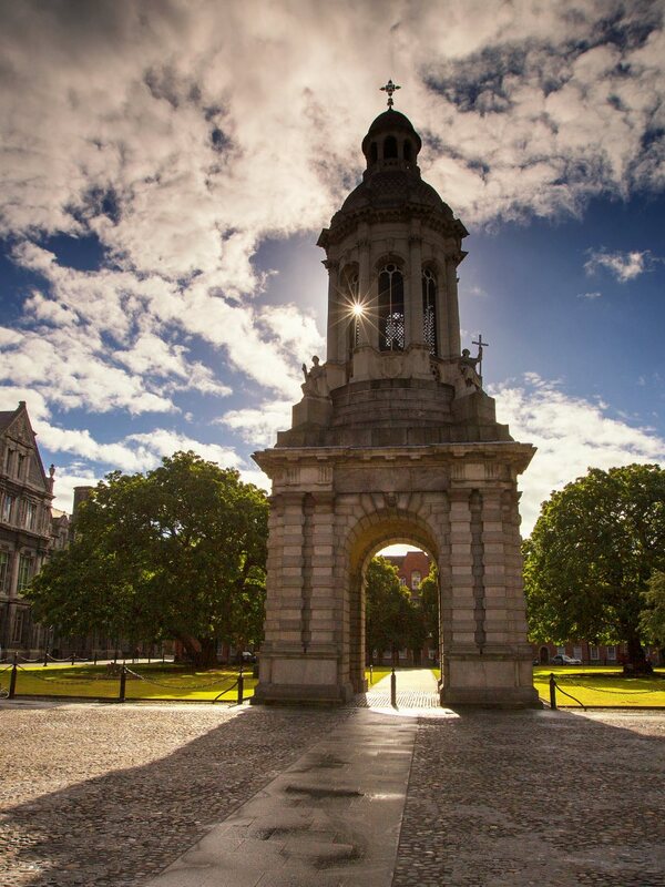 Interior of Trinity College Library Long Room with tall wooden shelves, busts, and suspended globe of Earth display.