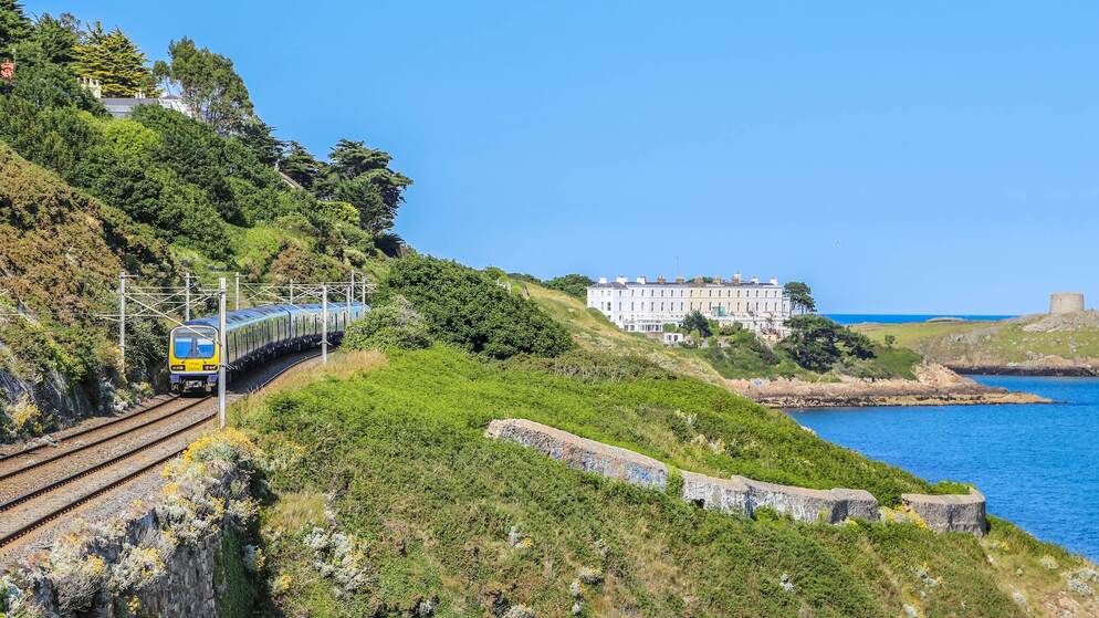 DART train travels along a coastal rail line near Dublin, promoting public transport travel across Ireland.