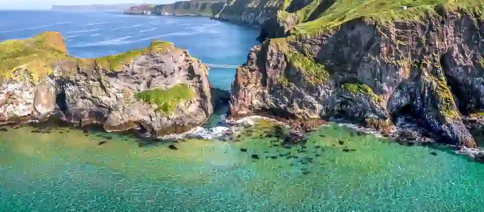 Carrick-a-Rede Rope Bridge spanning sea cliffs above clear turquoise water on the Antrim Coast, Northern Ireland.