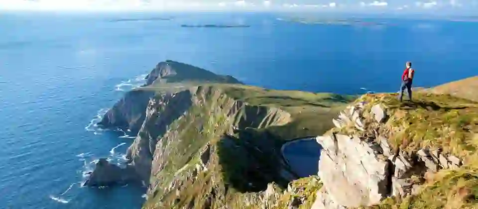 Hiker overlooking dramatic cliffs and Atlantic Ocean views on Achill Island, County Mayo.