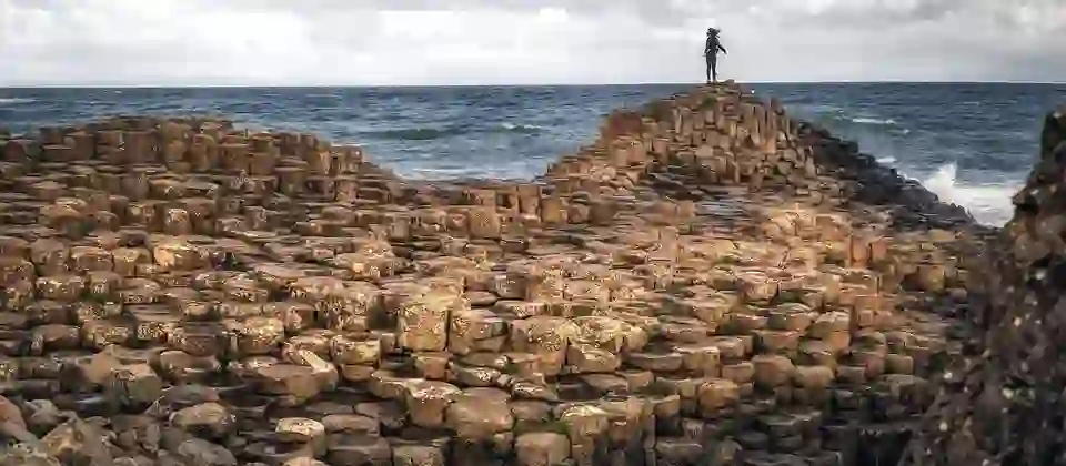 Visitor standing on the Giant’s Causeway basalt columns, County Antrim coastal landmark.